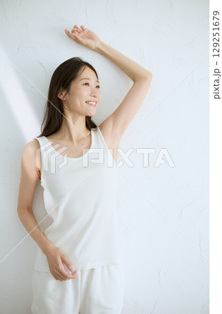 肌に触れてスキンケアする若い女性の笑顔 – 自然光・白背景 129251679