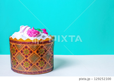 Baked Easter cake on blue background with copy space. Paschal sweet fruit bread decorating meringue, orthodox christian traditions Baked Easter cake on blue background with copy space. Paschal sweet fruit bread decorating meringue, orthodox christian traditions 129252100