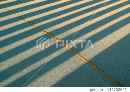Golden crack running through concrete with dramatic striped shadows during sunlight, highlighting textures and modern minimal design, AI Generative Golden crack running through concrete with dramatic striped shadows during sunlight, highlighting textures and modern minimal design, AI Generative 129252645