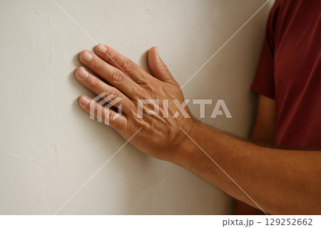Close up of adult male hand touching textured light wall, detail of skin and fingers against neutral background indoors, AI Generative 129252662