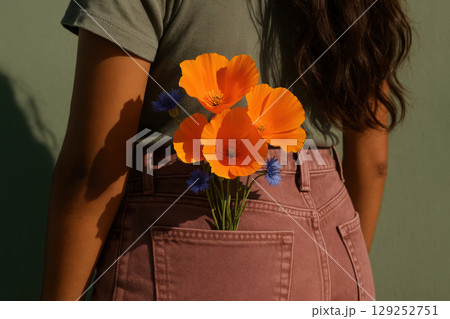 Vibrant orange poppy and blue cornflower bouquet in back pocket of woman wearing mauve pants under natural sunlight, AI Generative Vibrant orange poppy and blue cornflower bouquet in back pocket of woman wearing mauve pants under natural sunlight, AI Generative 129252751