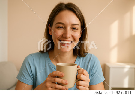 Smiling young woman enjoying a warm beverage in a cozy home environment, relaxes with a cup of coffee on a peaceful morning, AI Generative 129252811