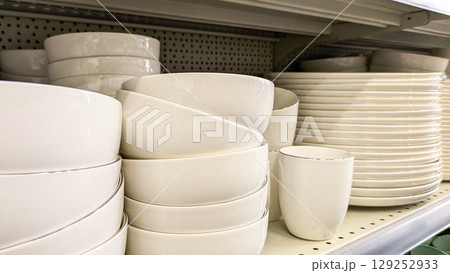 Various stacks of white ceramic plates and bowls on store shelves. Ideal for e-commerce, kitchenware or home decor Various stacks of white ceramic plates and bowls on store shelves. Ideal for e-commerce, kitchenware or home decor 129252933