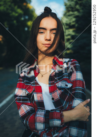 Woman with a plaid shirt and white shirt standing on a road Woman with a plaid shirt and white shirt standing on a road 129252950