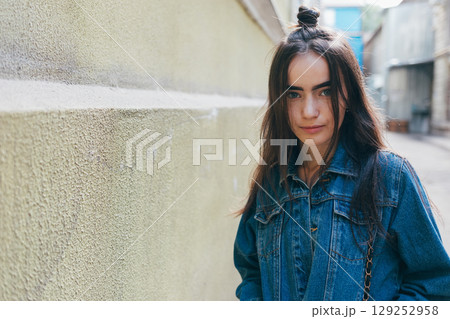 Woman with long hair is standing in front of a wall Woman with long hair is standing in front of a wall 129252958