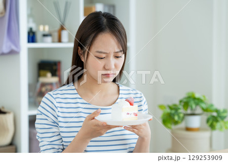 ケーキで悩む若い女性 ケーキで悩む若い女性 129253909
