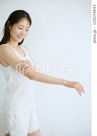 肌に触れてスキンケアする若い女性の笑顔 – 129254643