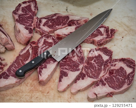 Rustic food photography showing traditional meal preparation with fresh raw beef, pork, and ingredients on butcher's table. Rustic food photography showing traditional meal preparation with fresh raw beef, pork, and ingredients on butcher's table. 129255471