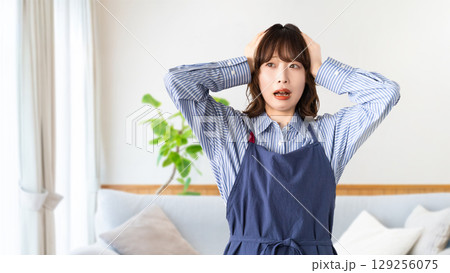 頭を抱えて悩むエプロン姿の女性 129256075