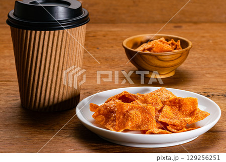 Crispy sweet pork slices in white ceramic dish with a paper coffee mug covered with black lid. Crispy sweet pork slices in white ceramic dish with a paper coffee mug covered with black lid. 129256251