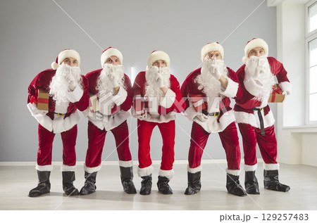 Happy New Year cute group posing in studio with gift box, partying wearing Santa Claus holiday 129257483