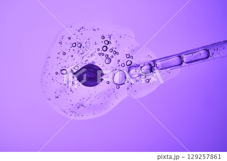 The beautiful texture of the serum with bubbles and a lilac flower pours out of the pipette. The beautiful texture of the serum with bubbles and a lilac flower pours out of the pipette. 129257861