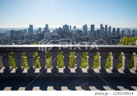Scenic view of Montreal's skyline showcasing its diverse architecture, with lush green trees in the foreground and the St. Lawrence River in background. Scenic view of Montreal's skyline showcasing its diverse architecture, with lush green trees in the foreground and the St. Lawrence River in background. 129259914
