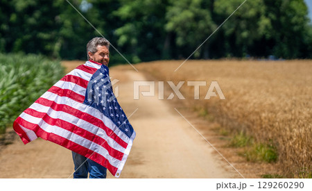 4th of July. American labor day. American flag and man farmer. Flag of USA. Independence day. Man in field. Man with American flag in crop field. Independence day of America. Copy space banner 129260290