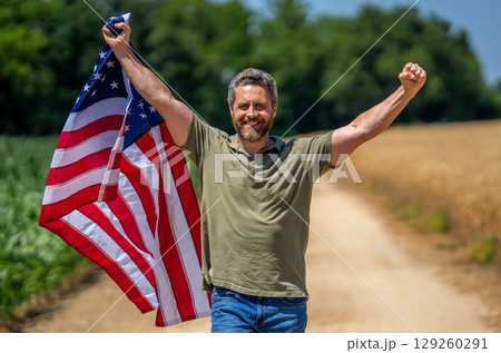 Labor day. American flag and man farmer, harvest. Flag of USA. Independence day. Man in field. Patriotic man with American flag in field. Independence day of America. 4th of July celebration Labor day. American flag and man farmer, harvest. Flag of USA. Independence day. Man in field. Patriotic man with American flag in field. Independence day of America. 4th of July celebration 129260291
