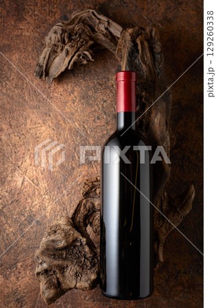 Bottle of red wine and old weathered snags. Bottle of red wine and old weathered snags. 129260338