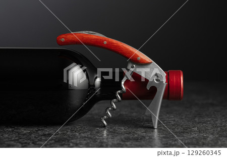 Corkscrew and bottle of red wine. 129260345