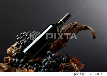 Bottle of red wine with blue grapes on old wooden snags. 129260348
