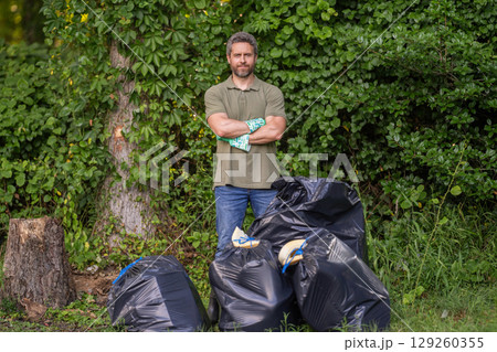 Save environment. Environment plastic pollution. Volunteer man collecting garbage in forest. Environmental protection. Man environmental activist. Environmental conservation. Recycling 129260355