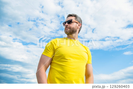 man wearing yellow shirt and sunglasses outdoor on sky background 129260403