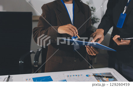 Focused young businessman signing agreement with skilled lawyer in eyeglasses. Concentrated financial advisor showing place for signature on paper contract document to male client at meeting in office Focused young businessman signing agreement with skilled lawyer in eyeglasses. Concentrated financial advisor showing place for signature on paper contract document to male client at meeting in office 129260459