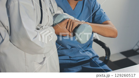 Person using hand weight with support of nurse 129260517