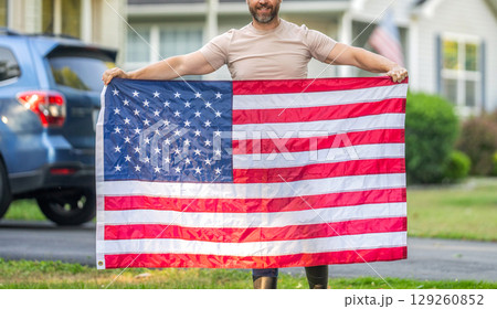 Man hold American flag outdoor. Patriotic man with patriotic symbol. American independence. National flag. Independence day. American Flag for Independence Day or 4th of July. Cropped view 129260852