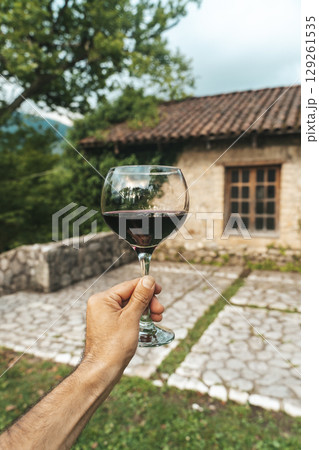 Red Wine Glass in Hand with Stone Cellar Background in France or Italy Red Wine Glass in Hand with Stone Cellar Background in France or Italy 129261535