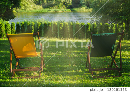 Couple enjoying a summer retreat together by the riverside in comfortable chairs 129261558