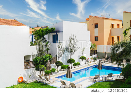 Tranquil resort in Greece featuring elegant white architecture and lush greenery Tranquil resort in Greece featuring elegant white architecture and lush greenery 129261562