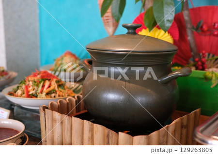 Stewed potato, carrot, onion, tomato and prunes in a clay pots with lid on wooden background, close up, top view 129263805