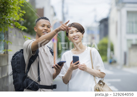 外国人の男性に道を説明をする女性　 129264050