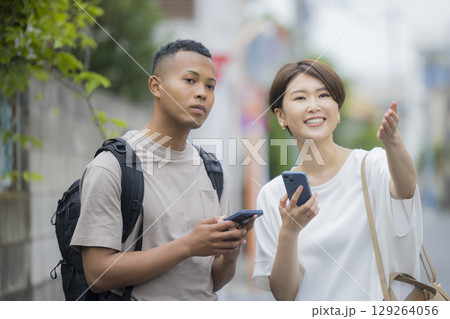 外国人の男性に道を説明をする女性 外国人の男性に道を説明をする女性 129264056