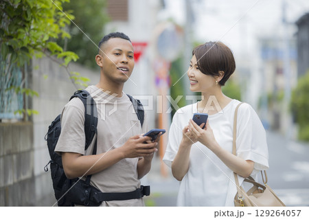 外国人の男性に道を説明をする女性　 129264057