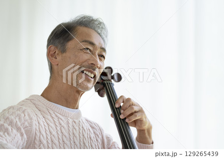 チェロを弾く笑顔の60代の男性 129265439