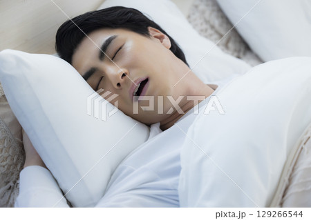 ベッドでいびきをかきながら眠る若い男性　 129266544