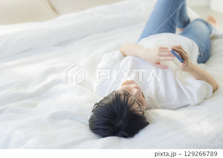 ベッドでスマホを見る女性 129266789