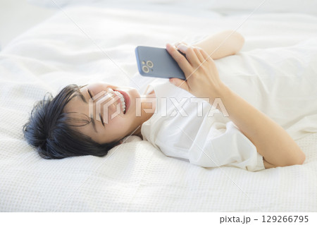 ベッドでスマホを見る女性 129266795