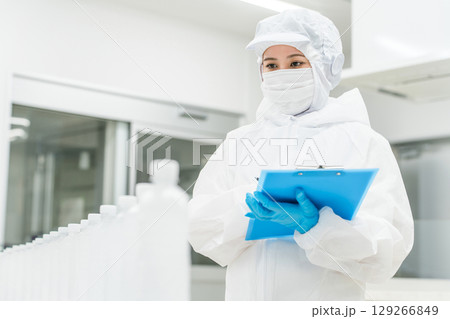 水工場,飲料メーカーで働くペットボトルの水をチェックする防塵服姿の製造スタッフ（飲料メーカー） 129266849