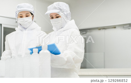 水工場,飲料メーカーで働くペットボトルの水をチェックする防塵服姿の製造スタッフ（飲料メーカー） 129266852