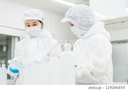 水工場,飲料メーカーで働くペットボトルの水をチェックする防塵服姿の製造スタッフ（飲料メーカー） 129266859