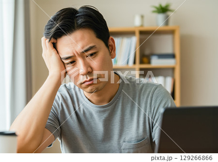 ノートブックPCを見ながら苦慮している男性 129266866