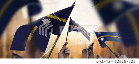 Nauru flags in their hands on a blurred urban background 129267523