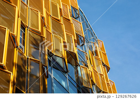 Modern Building Facade with Yellow Geometric Sunshades on Glass Windows Modern Building Facade with Yellow Geometric Sunshades on Glass Windows 129267626