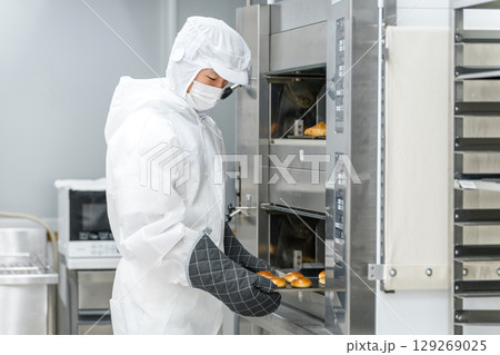 パン工場,食品工場で働く防塵服,クリーンスーツを着た製造スタッフの男性 129269025