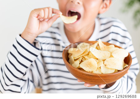 お菓子を食べる小学生の男の子 お菓子を食べる小学生の男の子 129269688