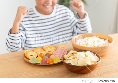 たくさんのお菓子を見て喜ぶ小学生の男の子 129269740