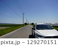 真っ直ぐな道を進む白い車 129270151