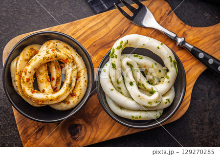 Marinated squid rings in bowl on black table. Top view. Marinated squid rings in bowl on black table. Top view. 129270285