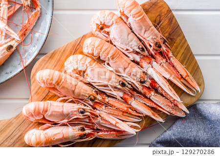 Scampi langoustine on cutting board on white table. Top view. 129270286